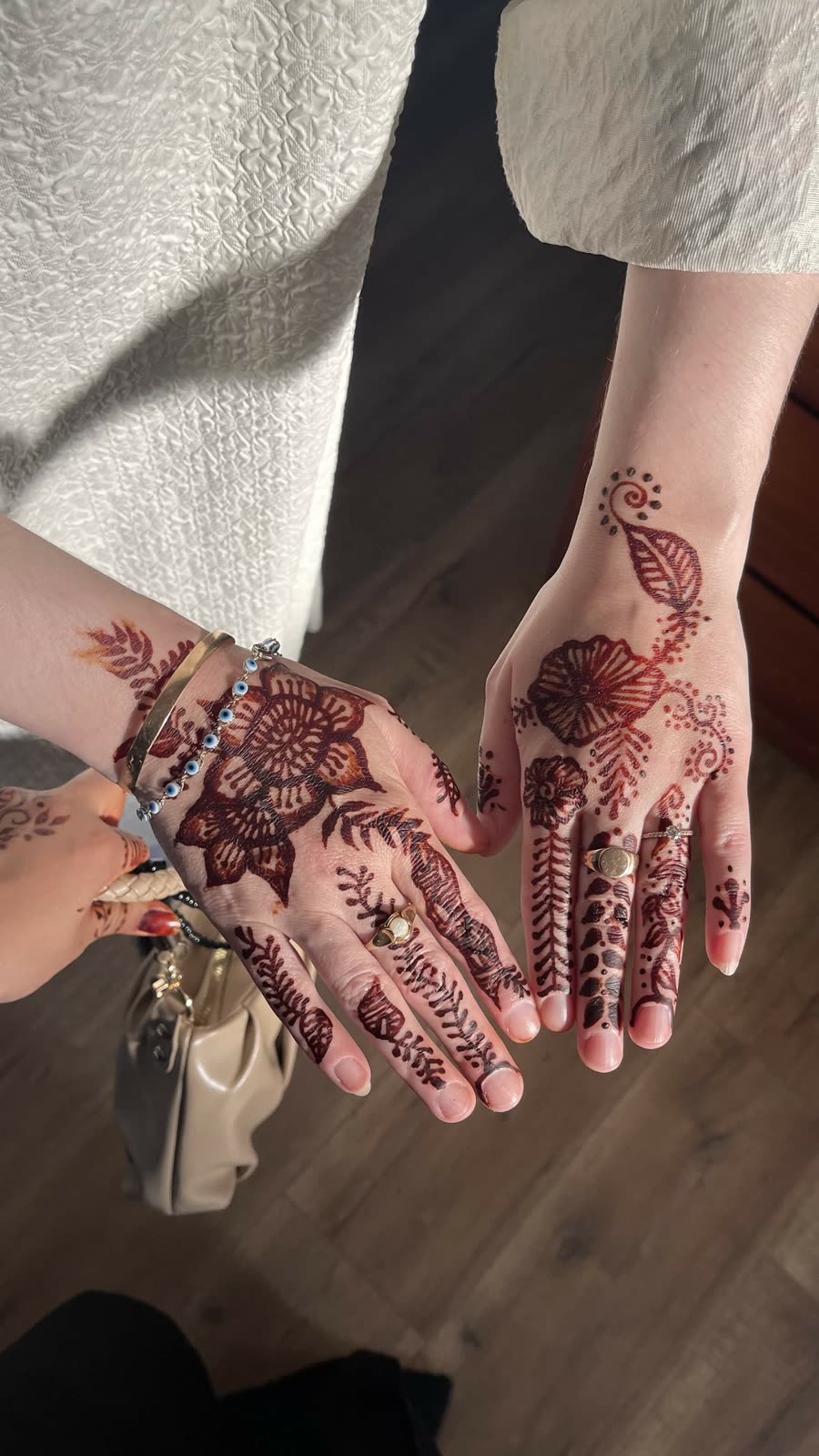 Reddish natural henna florals across two pairs of hands
